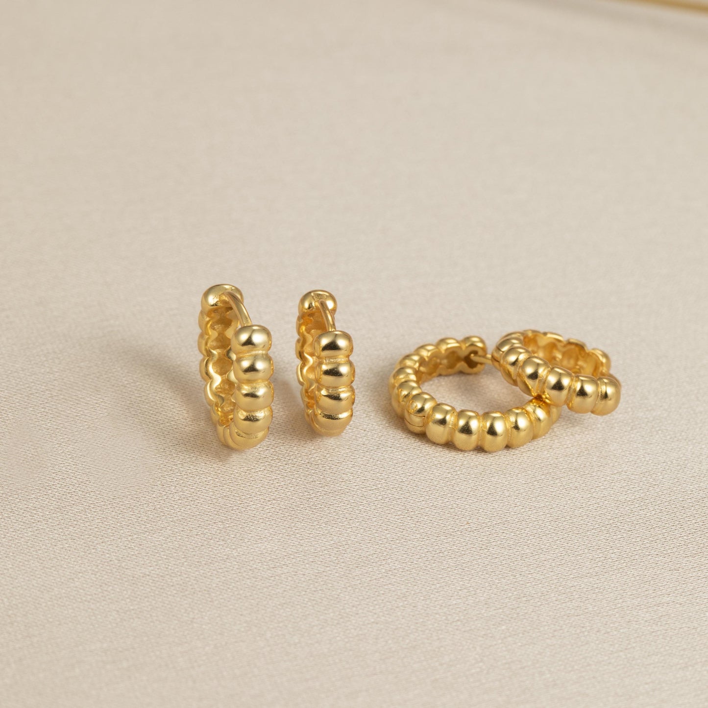 a pair of gold earrings sitting on top of a table