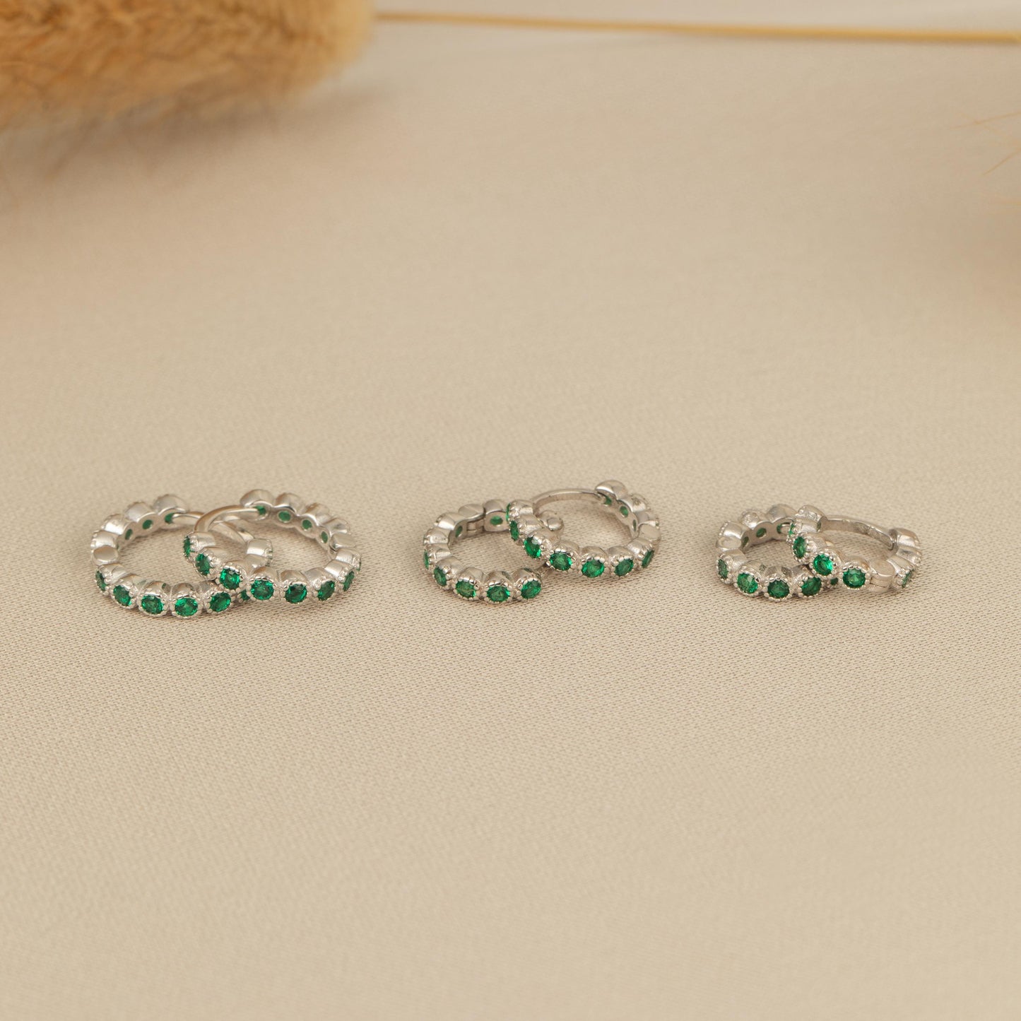 three pairs of silver rings with green stones