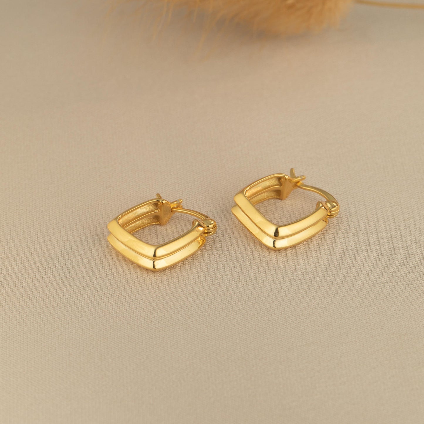 a pair of gold earrings sitting on top of a table