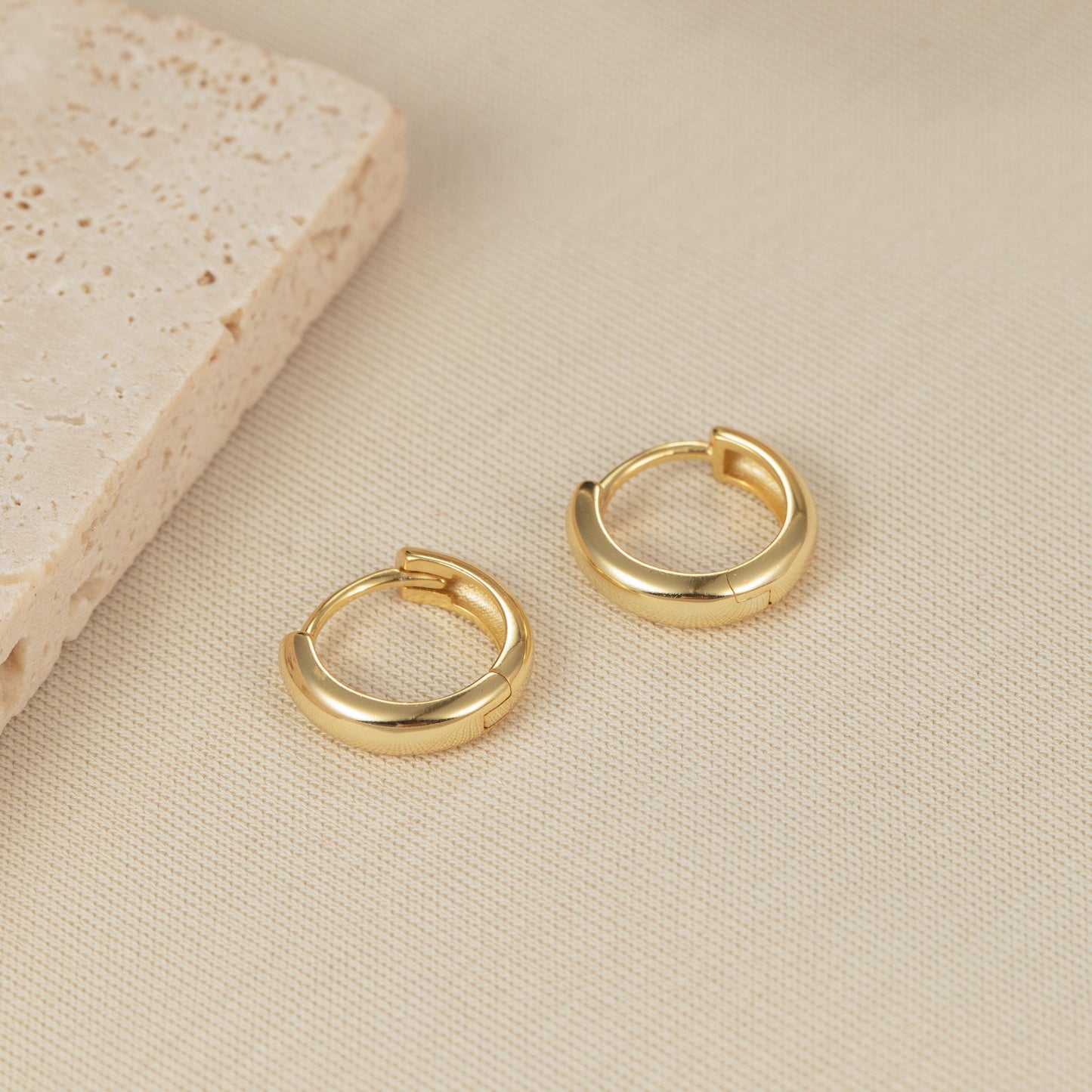 a pair of gold hoop earrings sitting on top of a table