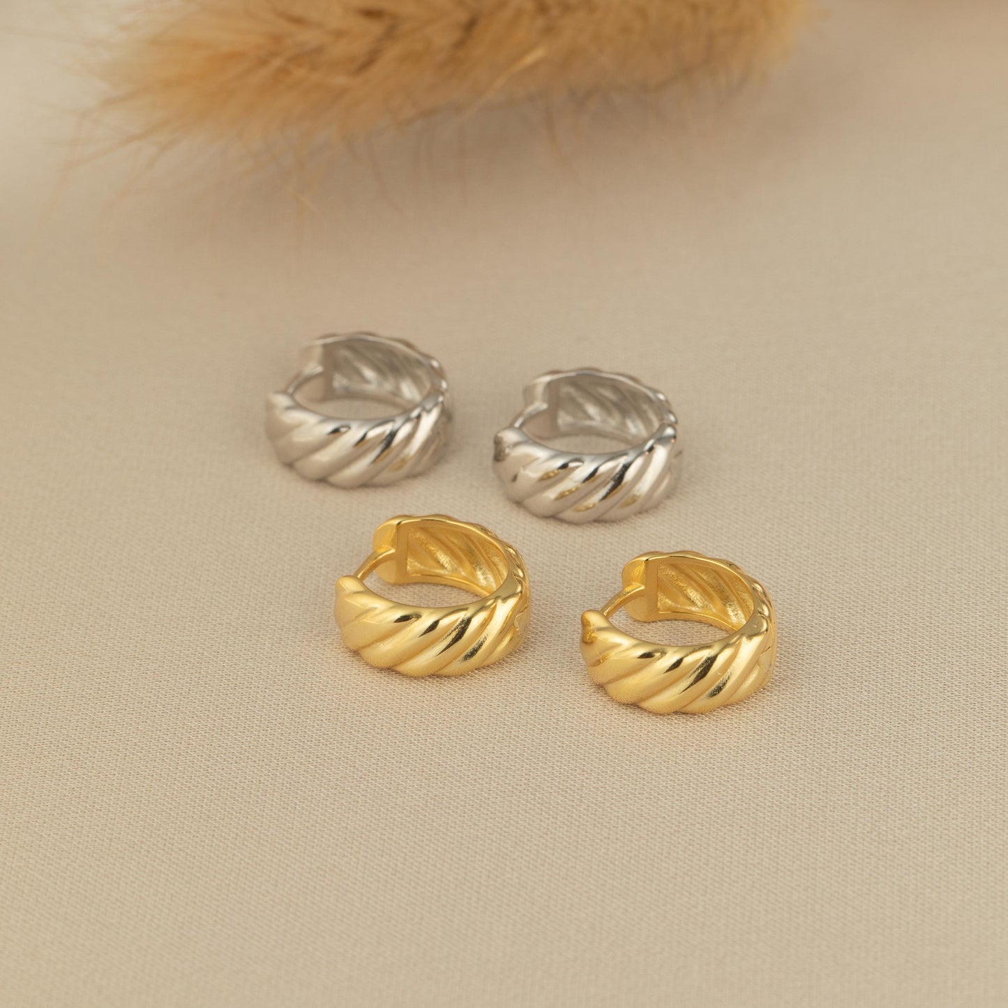 three pairs of gold and silver earrings on a table