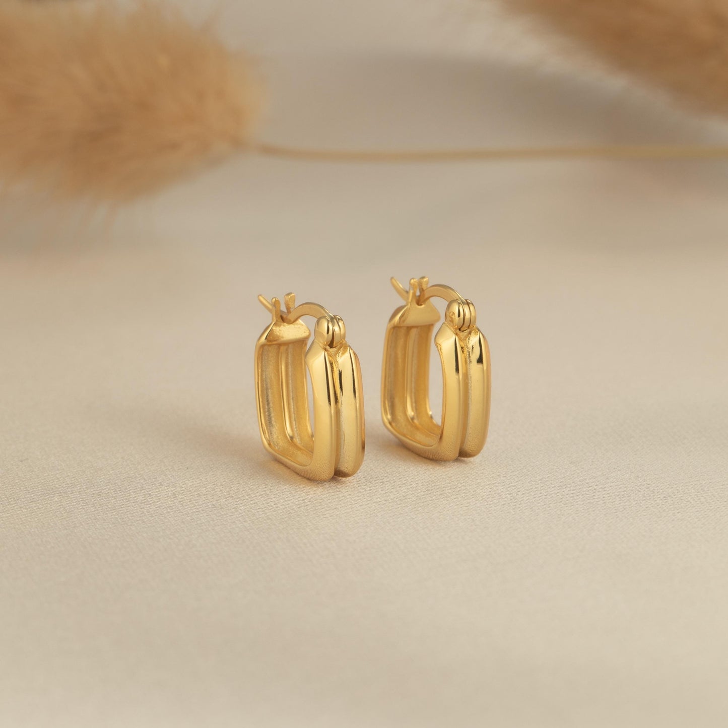 a pair of gold earrings on a white surface