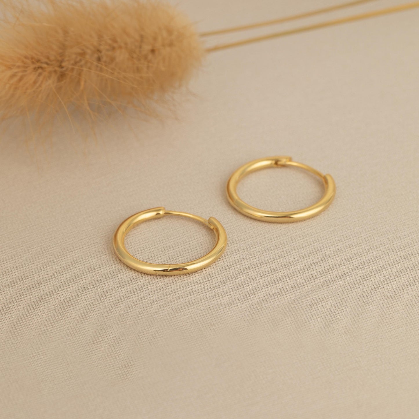 a pair of gold hoop earrings sitting on top of a table