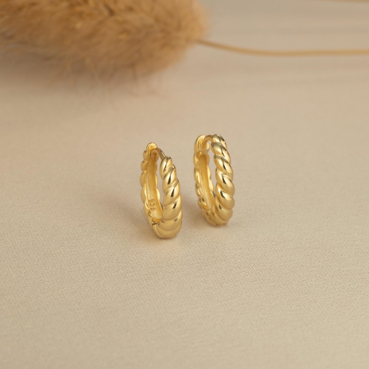 a pair of gold hoop earrings sitting on top of a table