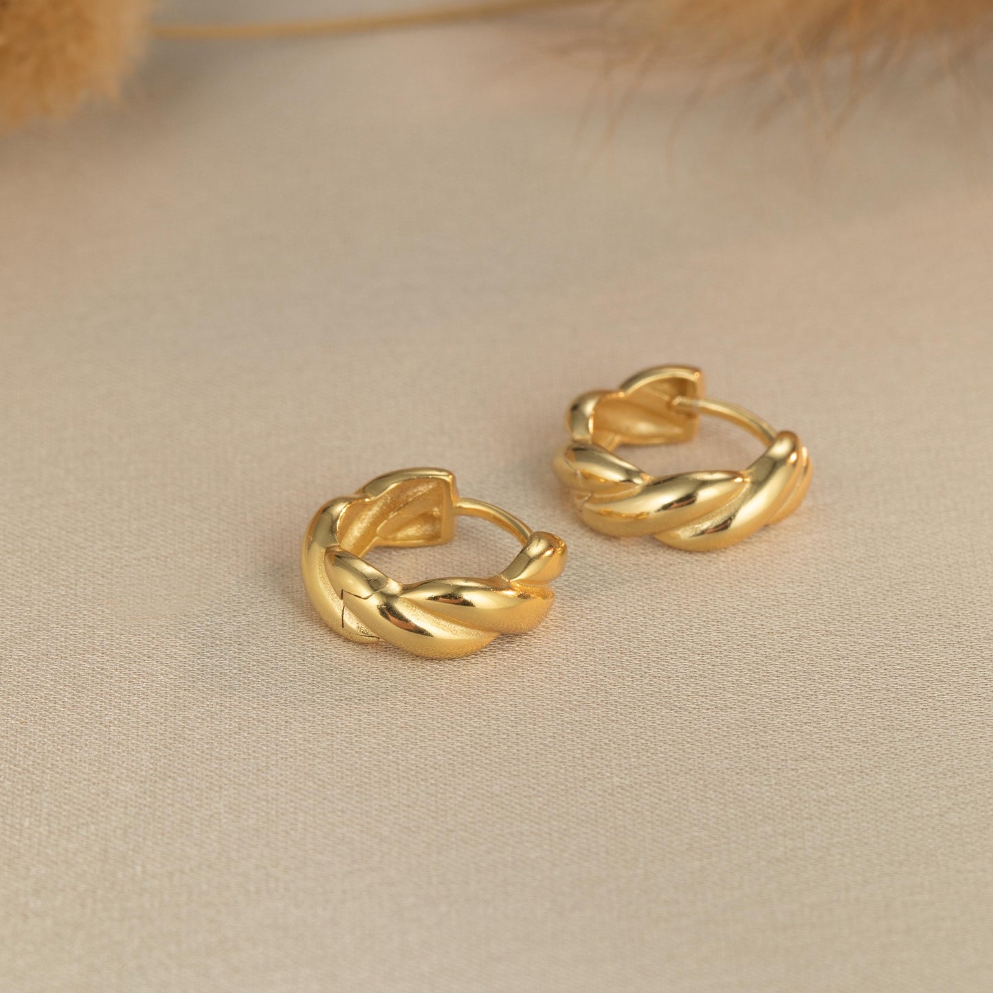 a pair of gold earrings sitting on top of a table