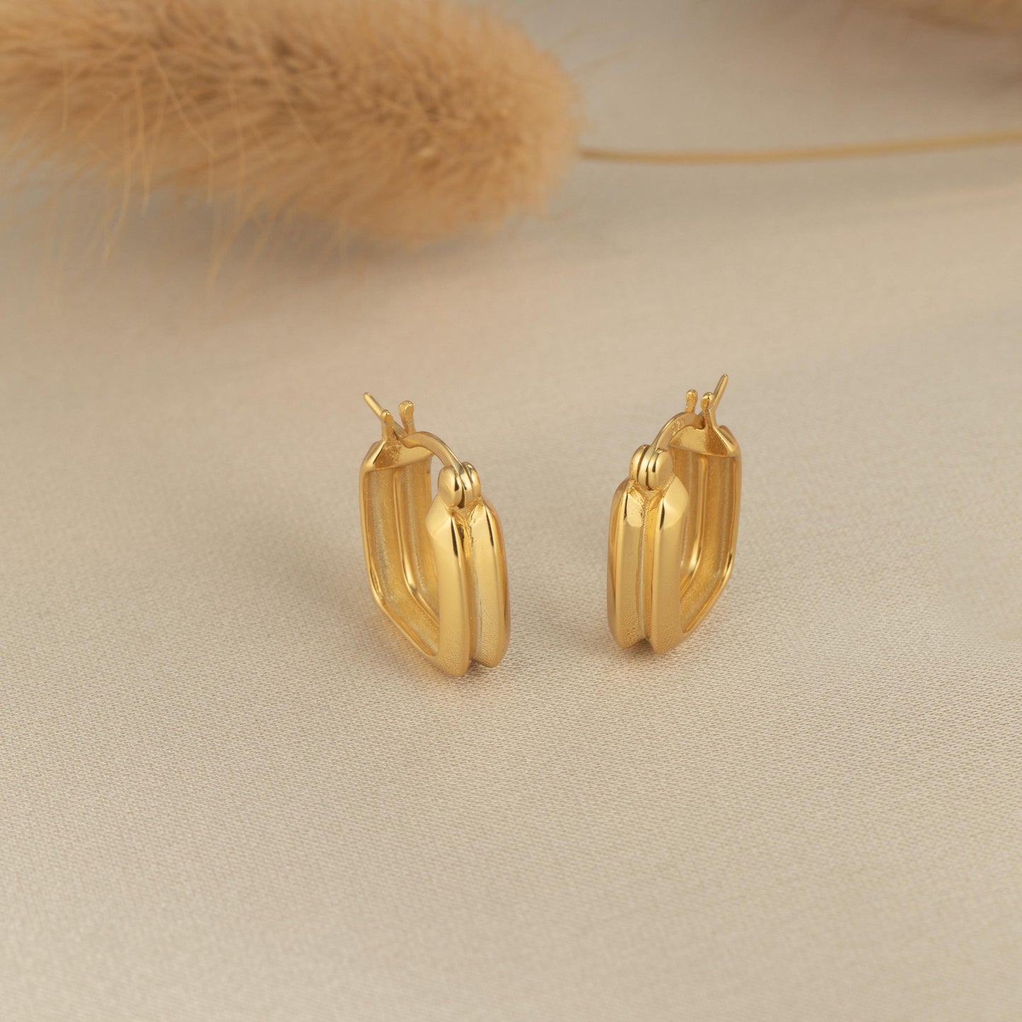 a pair of gold earrings sitting on top of a table