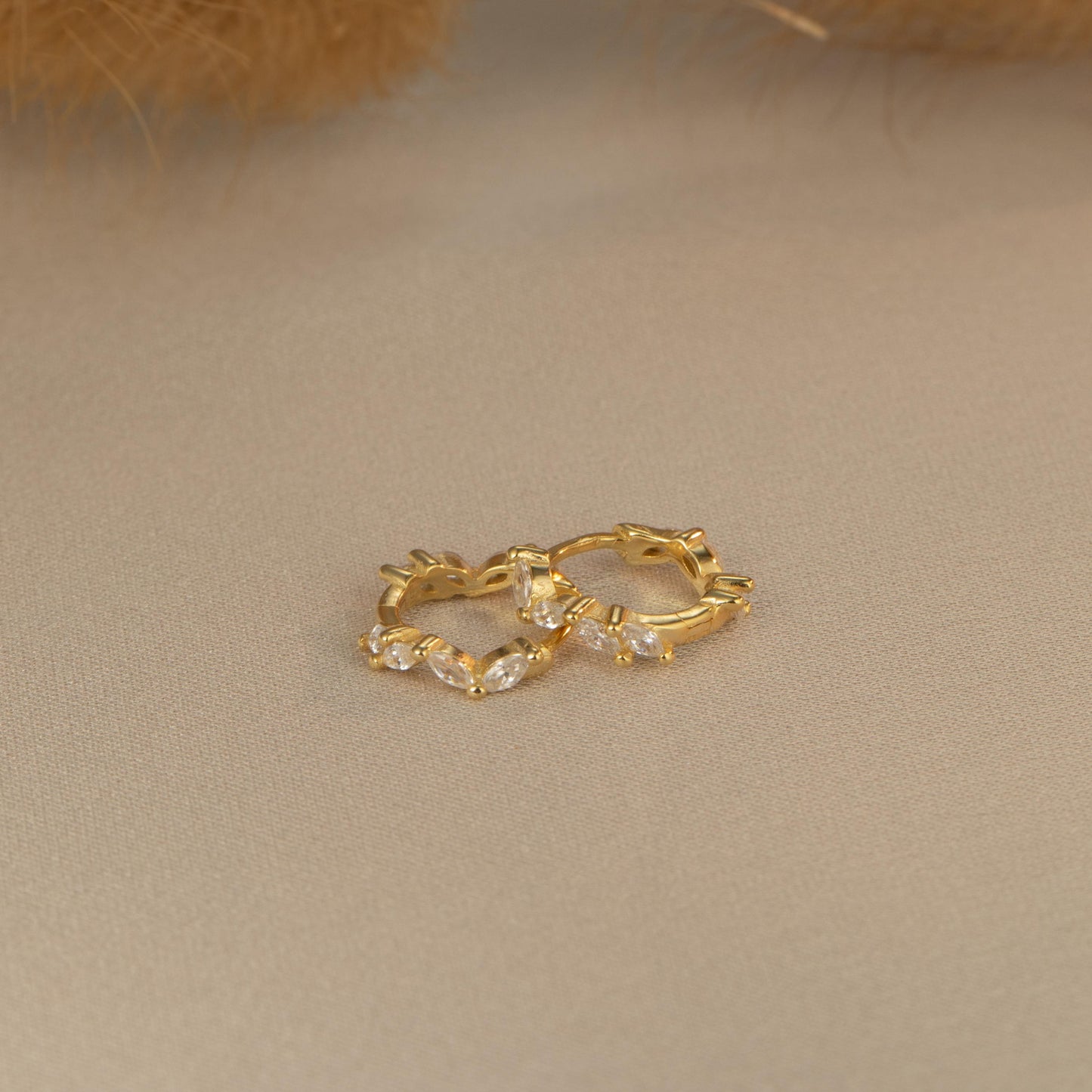 a pair of gold earrings sitting on top of a table