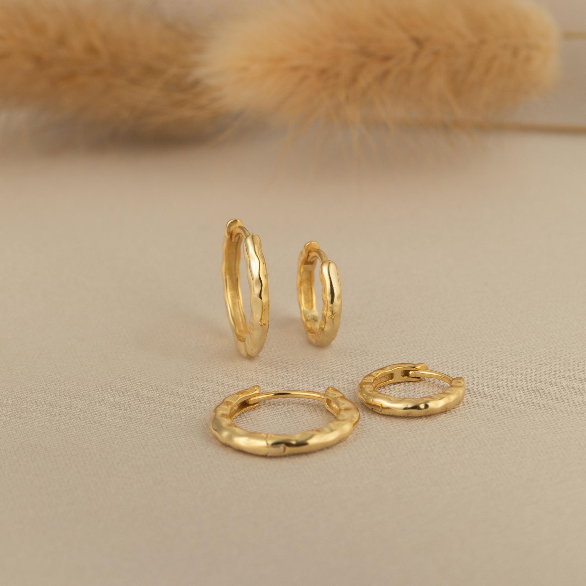 a pair of gold hoop earrings and a pair of small gold hoop earrings