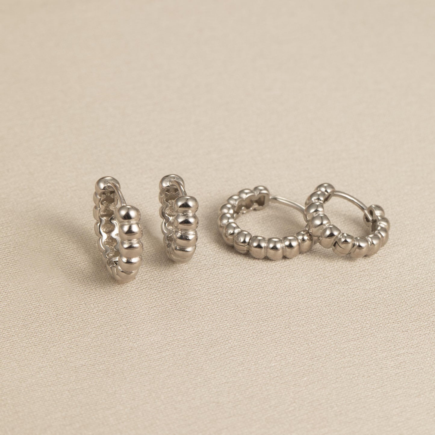 a pair of silver earrings sitting on top of a table