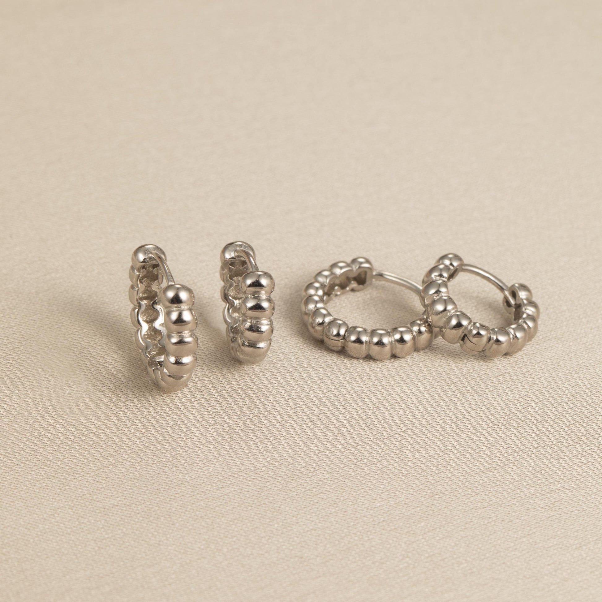 a pair of silver earrings sitting on top of a table