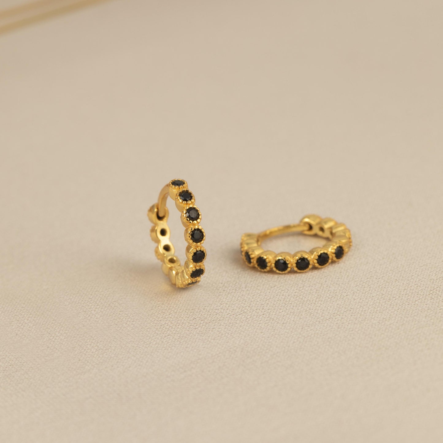 a pair of gold earrings with black stones