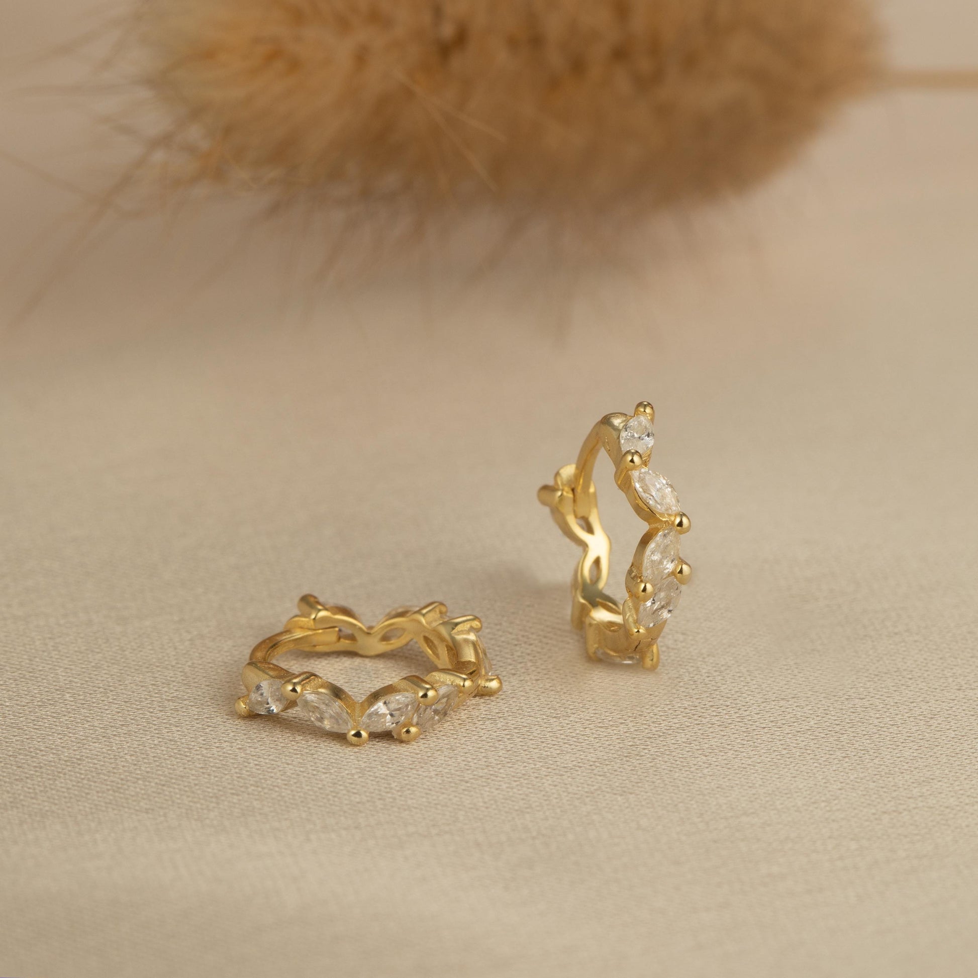 a pair of gold earrings sitting on top of a table