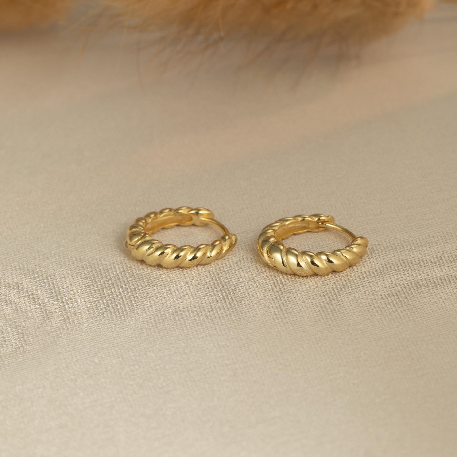 a pair of gold hoop earrings sitting on top of a table