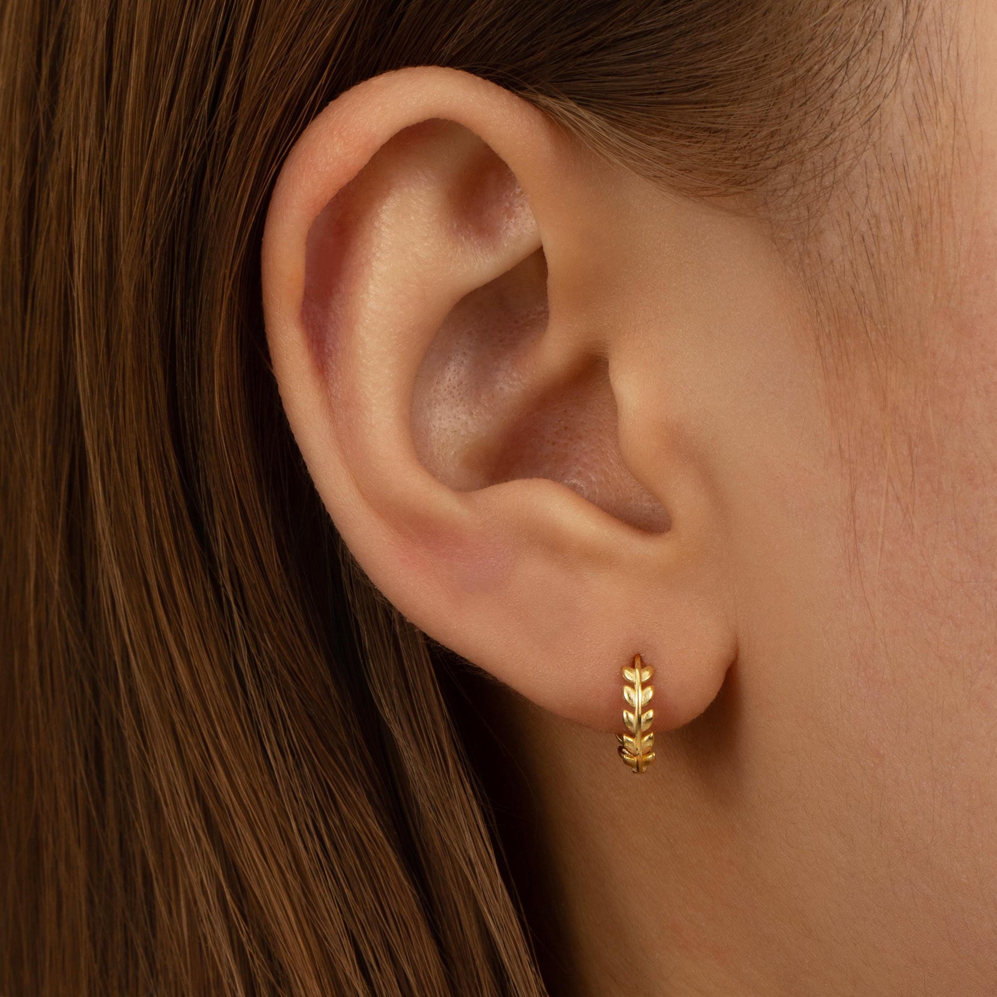 a close up of a person&#39;s ear wearing a gold earring