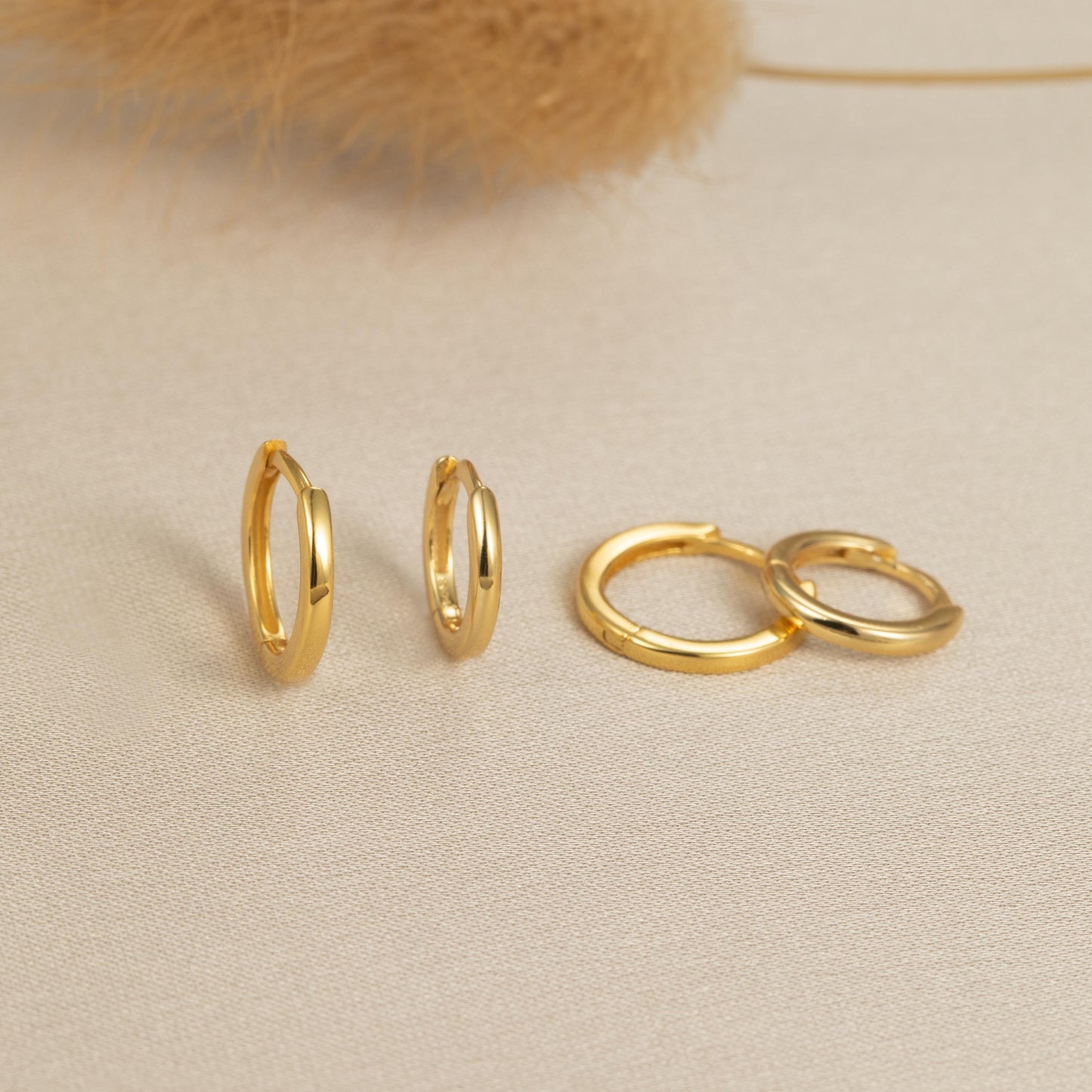 a pair of gold hoop earrings sitting on top of a table