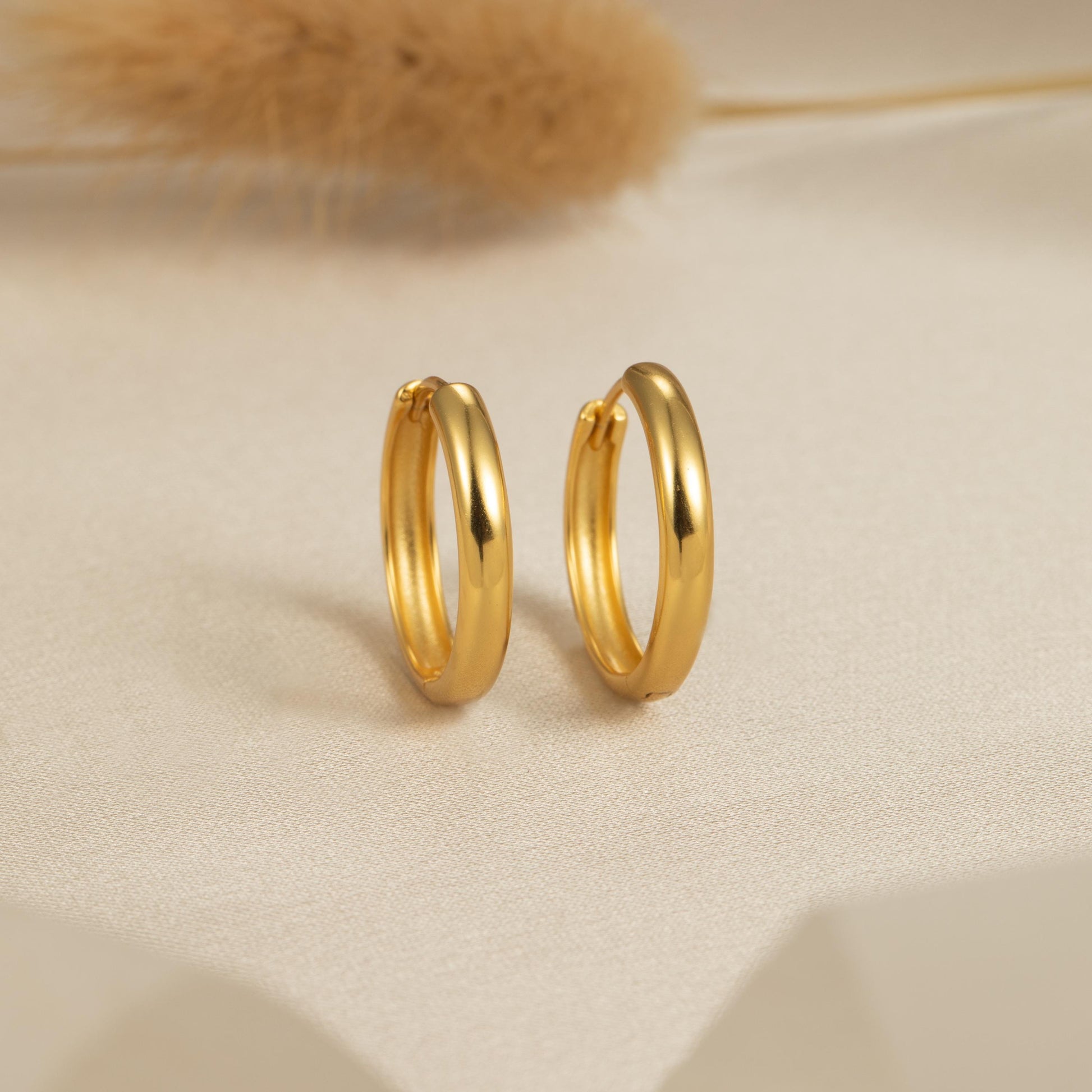 a pair of gold hoop earrings sitting on top of a table