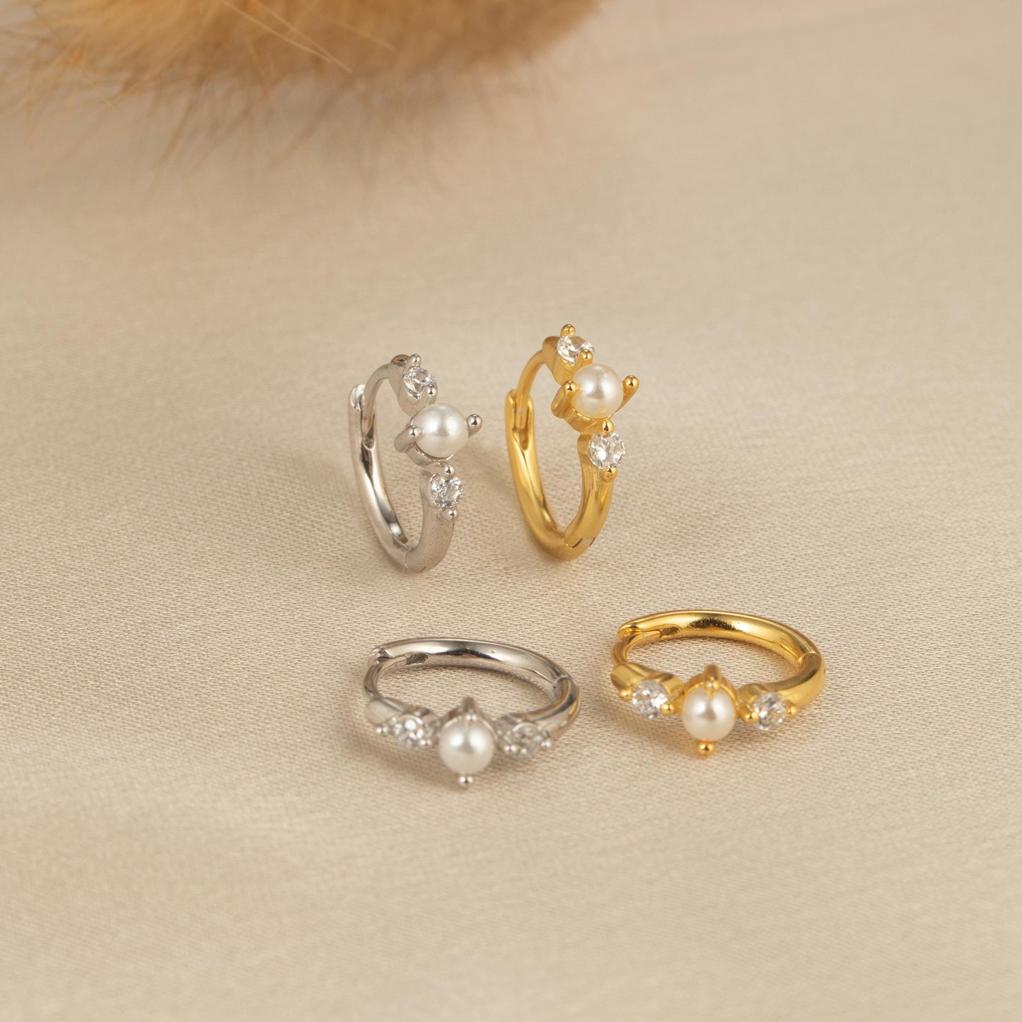 three rings with pearls and a feather on a table