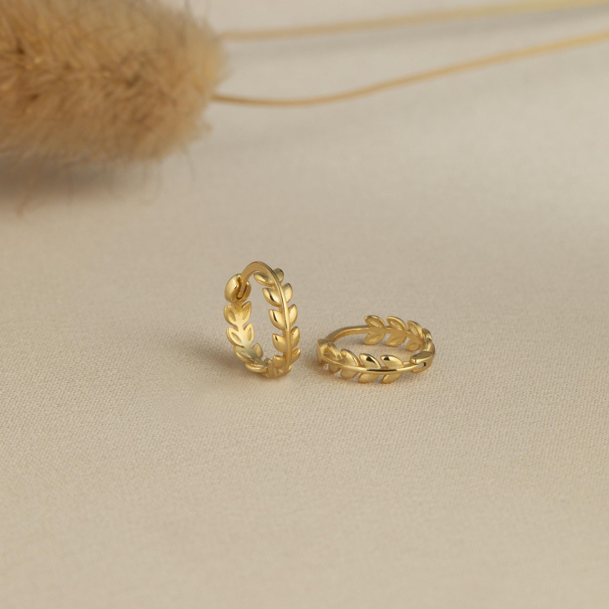 a pair of gold earrings sitting on top of a table