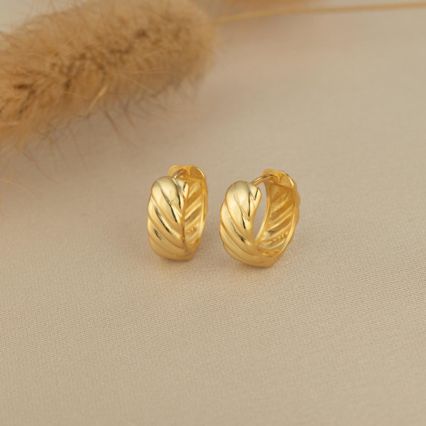 a pair of gold earrings sitting on top of a table