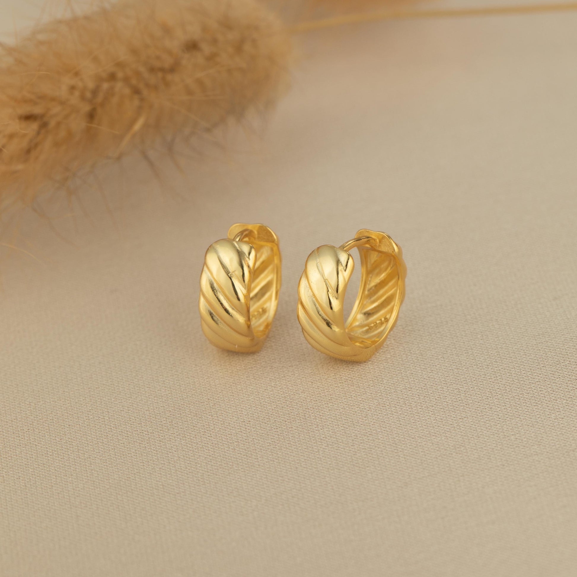 a pair of gold earrings sitting on top of a table
