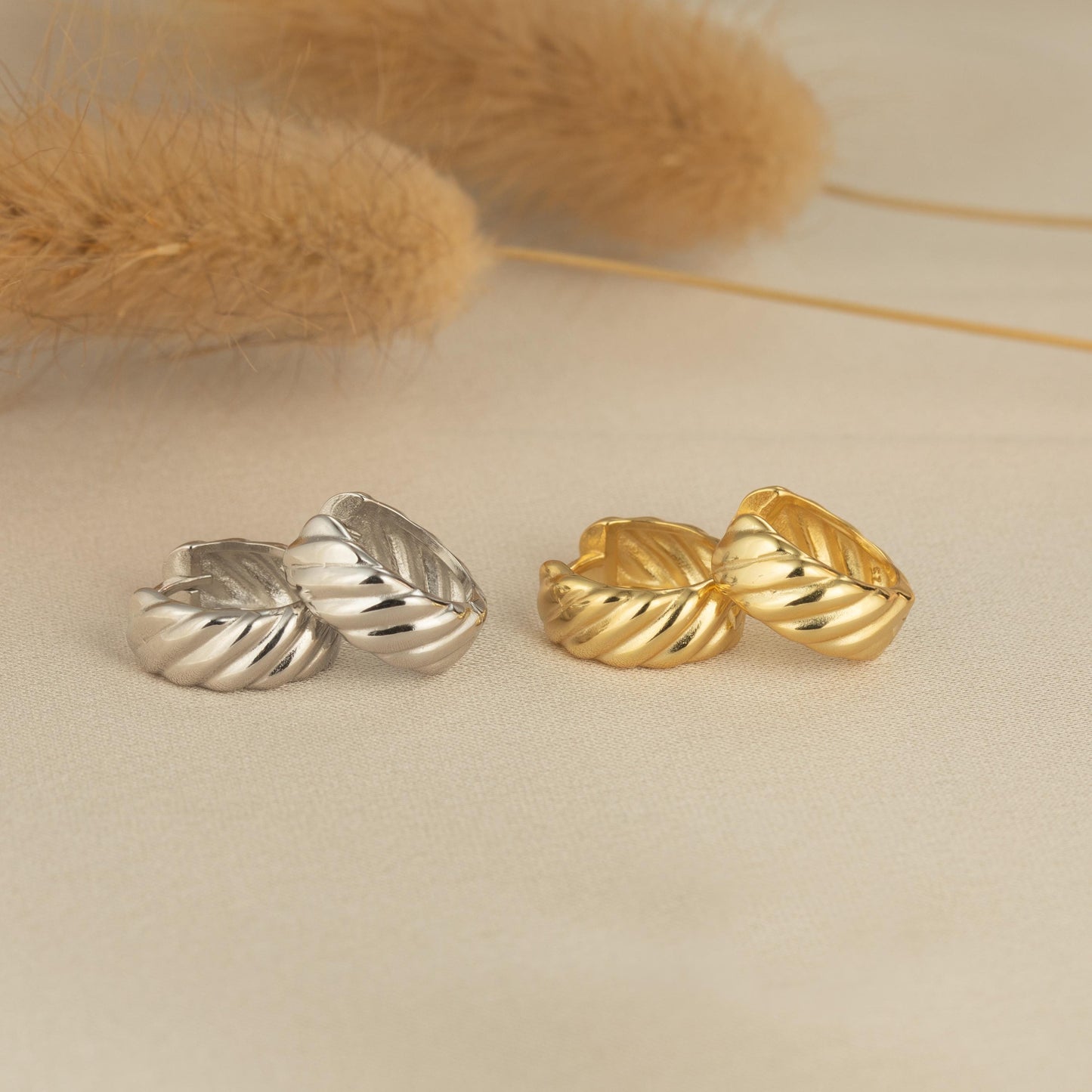 a pair of gold and silver earrings on a white surface