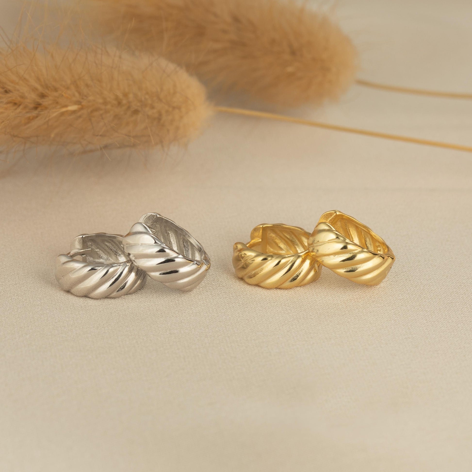 a pair of gold and silver earrings on a white surface