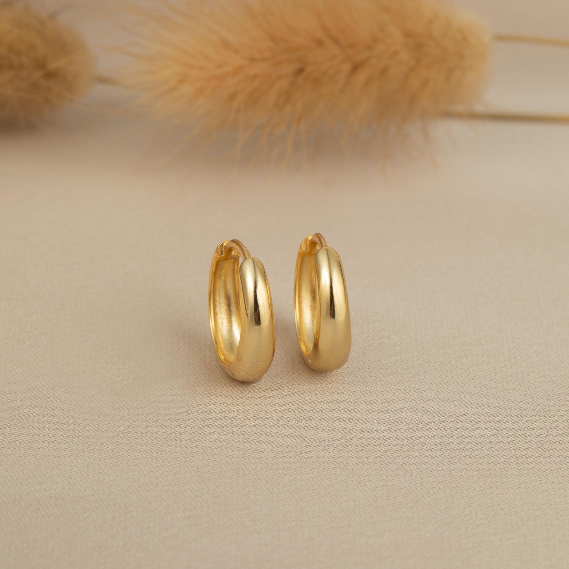 a pair of gold earrings sitting on top of a table