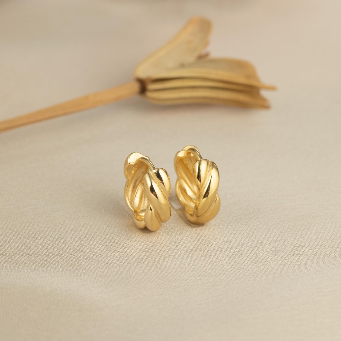 a pair of gold earrings sitting on top of a table