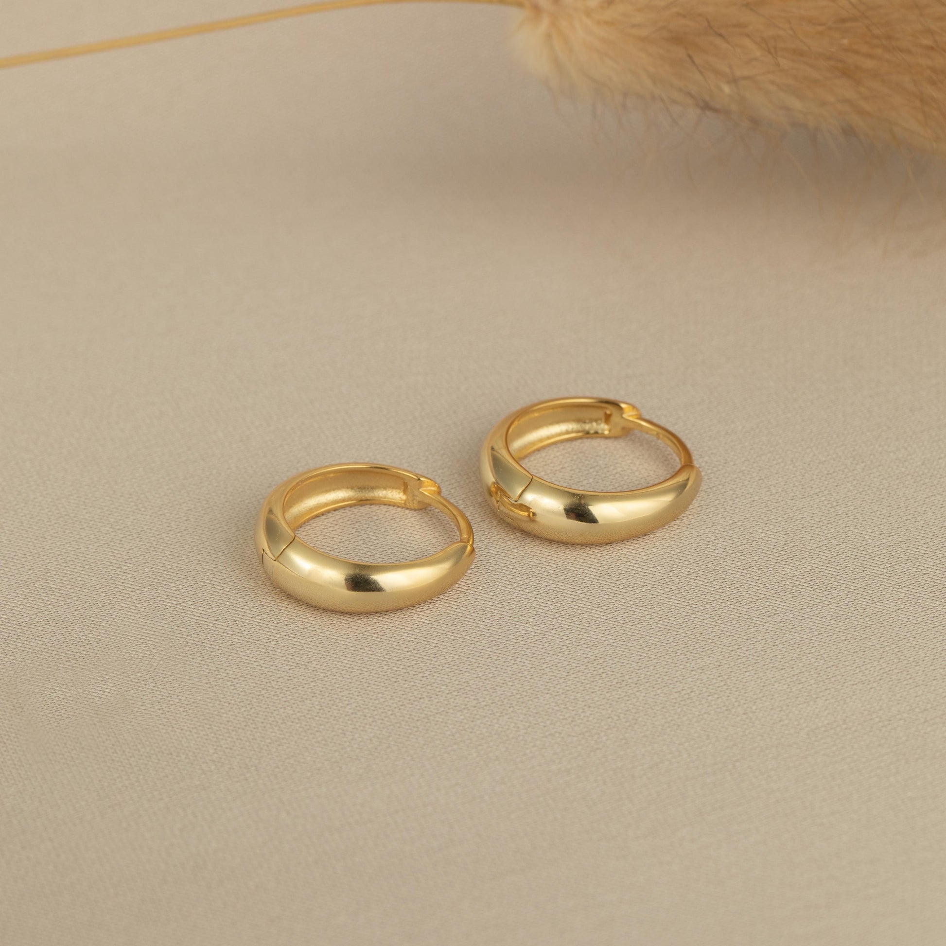a pair of gold hoop earrings sitting on top of a table