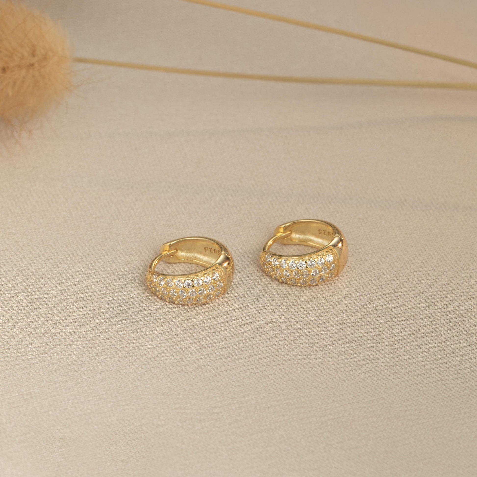 a pair of gold colored earrings sitting on top of a table