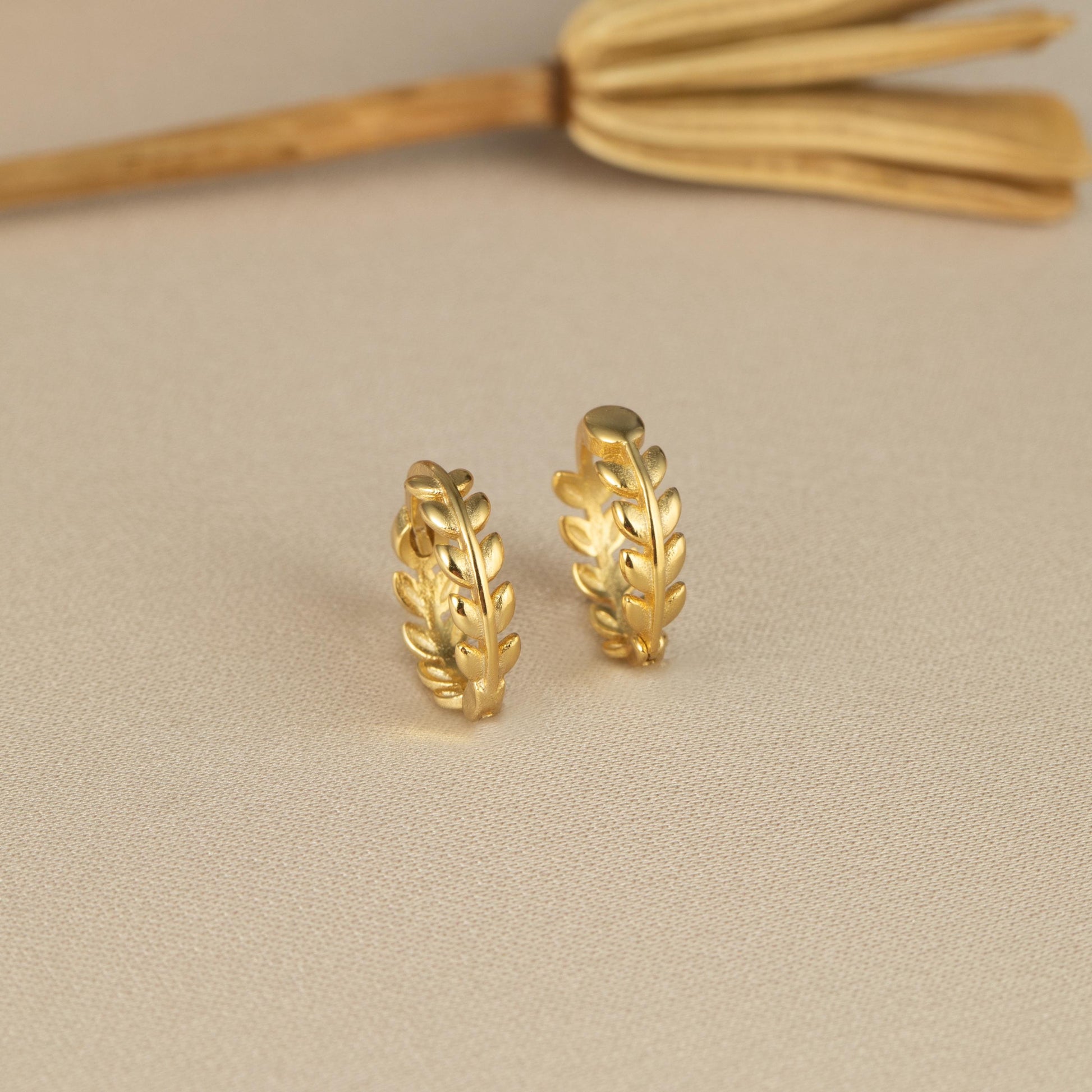 a pair of gold earrings sitting on top of a table