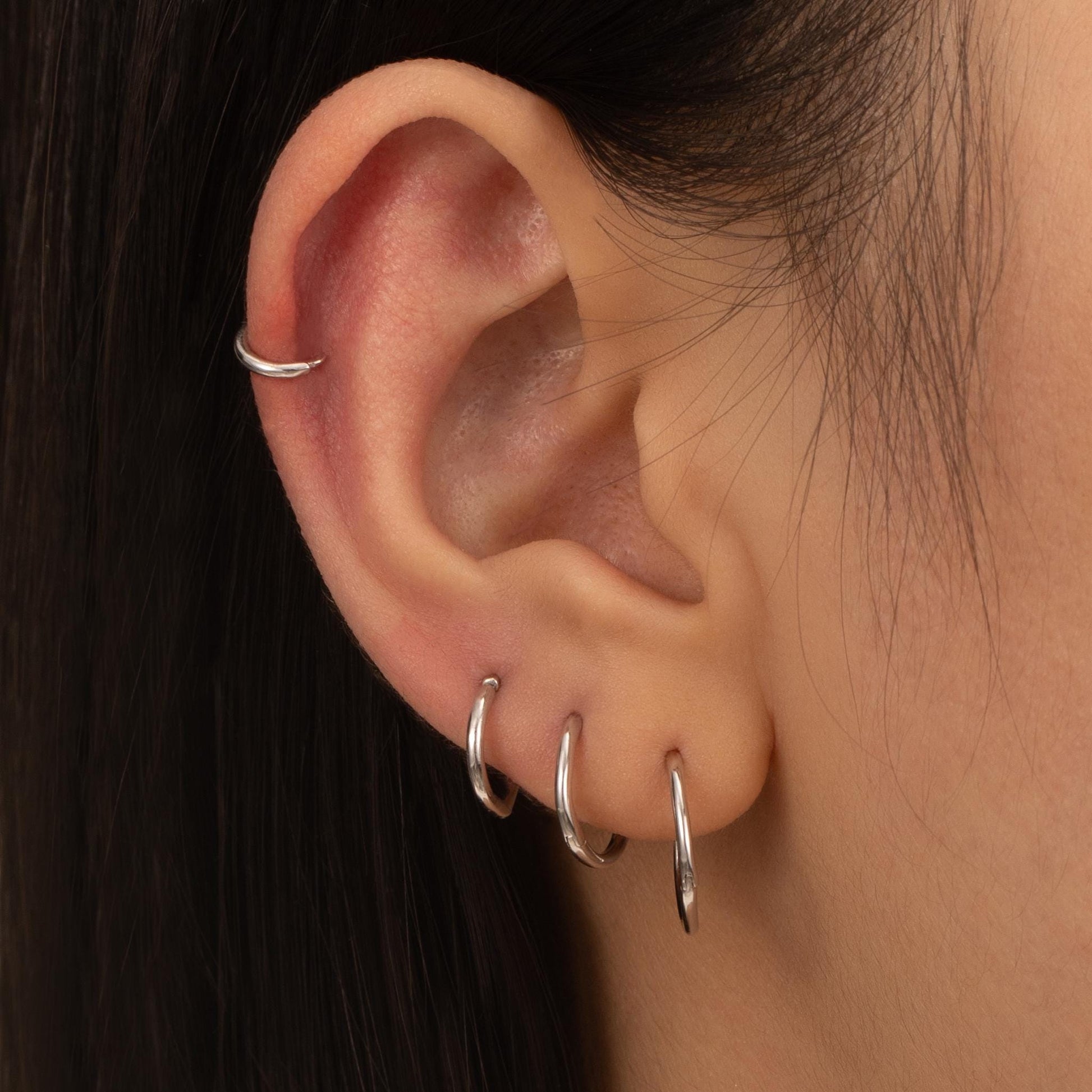 a close up of a person&#39;s ear with a pair of silver hoops