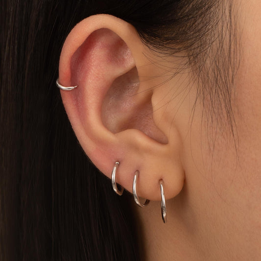 a close up of a person&#39;s ear with a pair of silver hoops