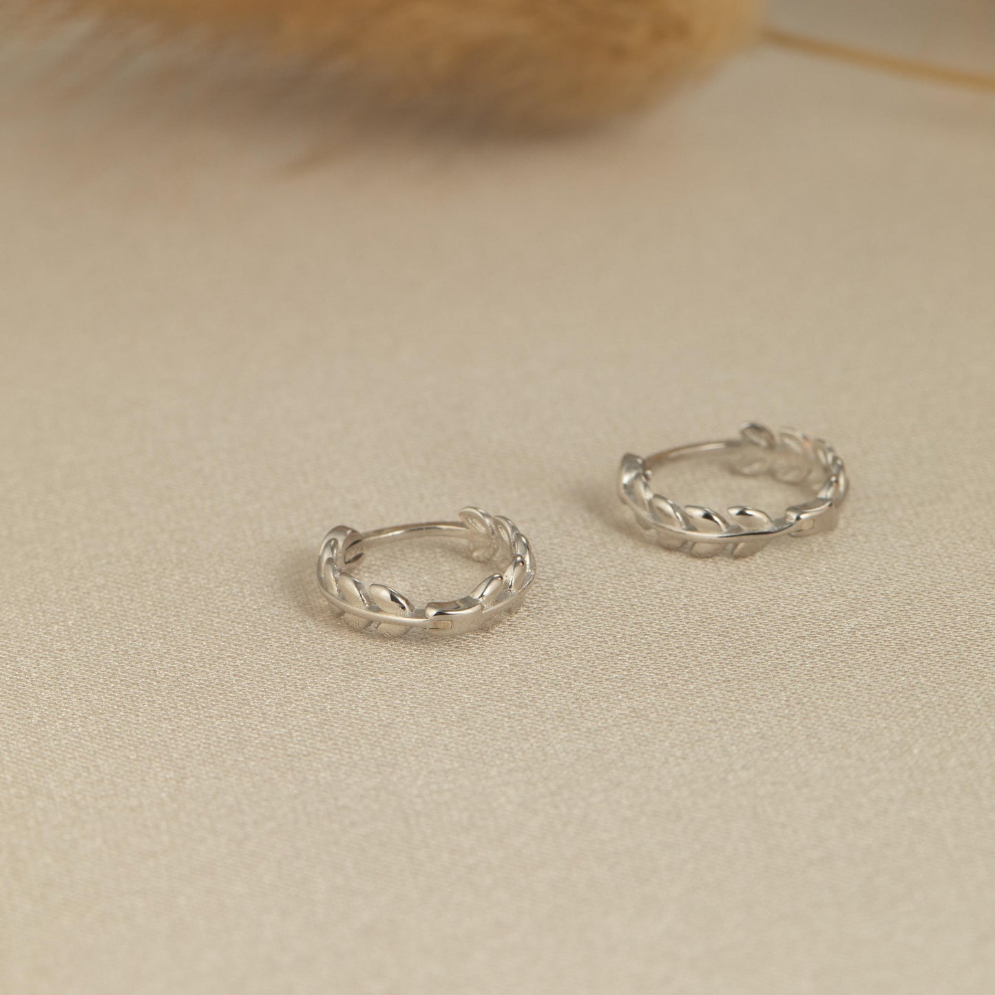 a pair of silver hoop earrings sitting on top of a table