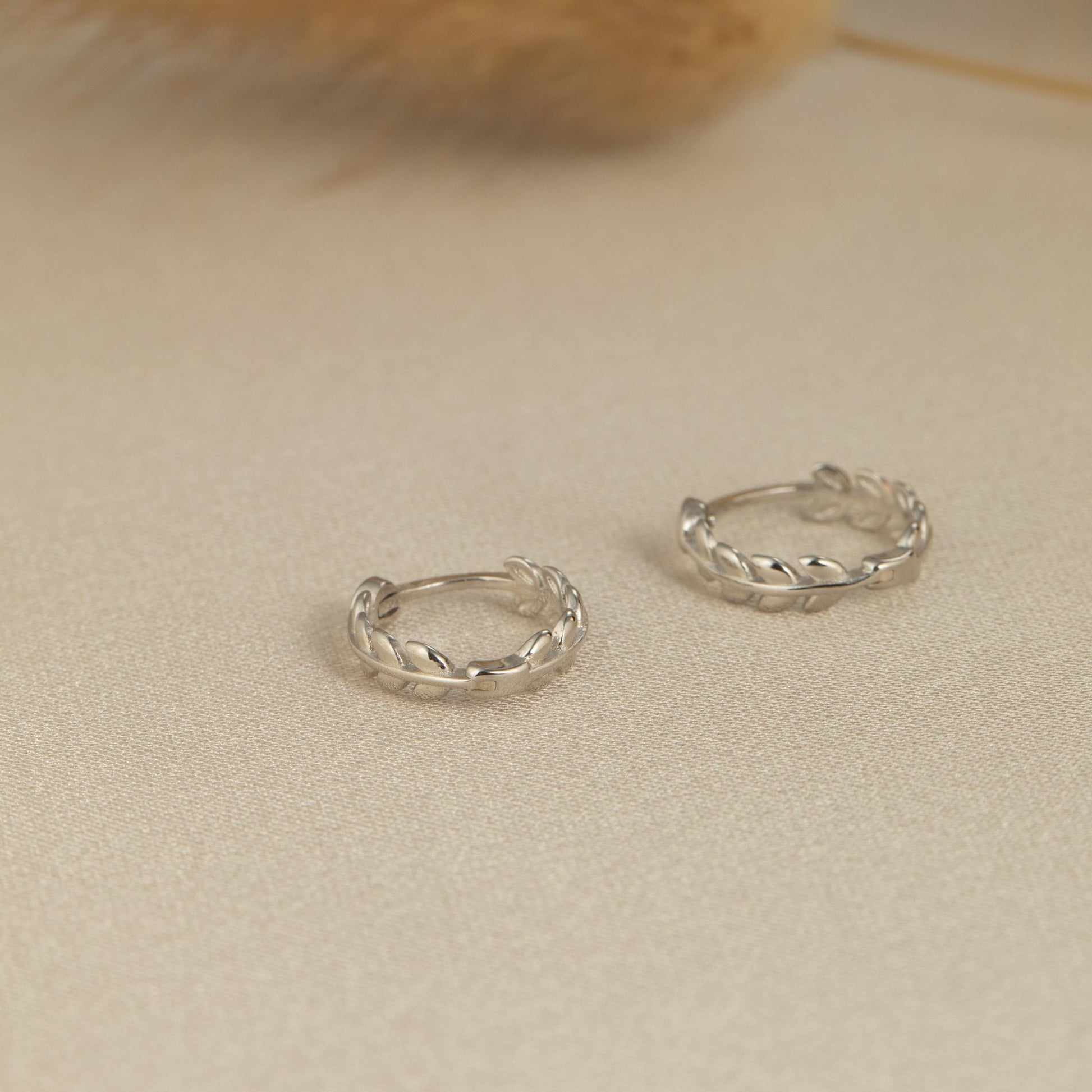 a pair of silver hoop earrings sitting on top of a table
