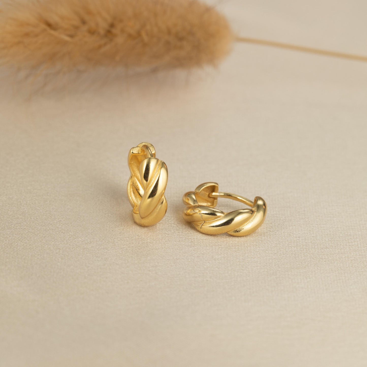 a pair of gold earrings sitting on top of a table