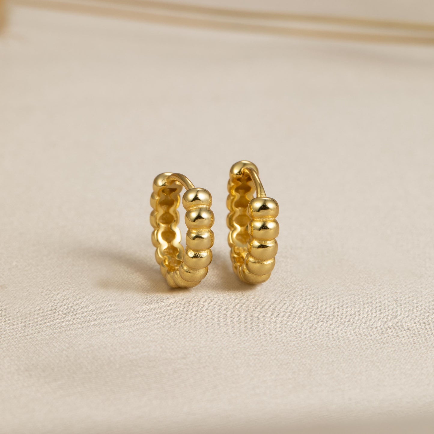 a pair of gold earrings sitting on top of a table