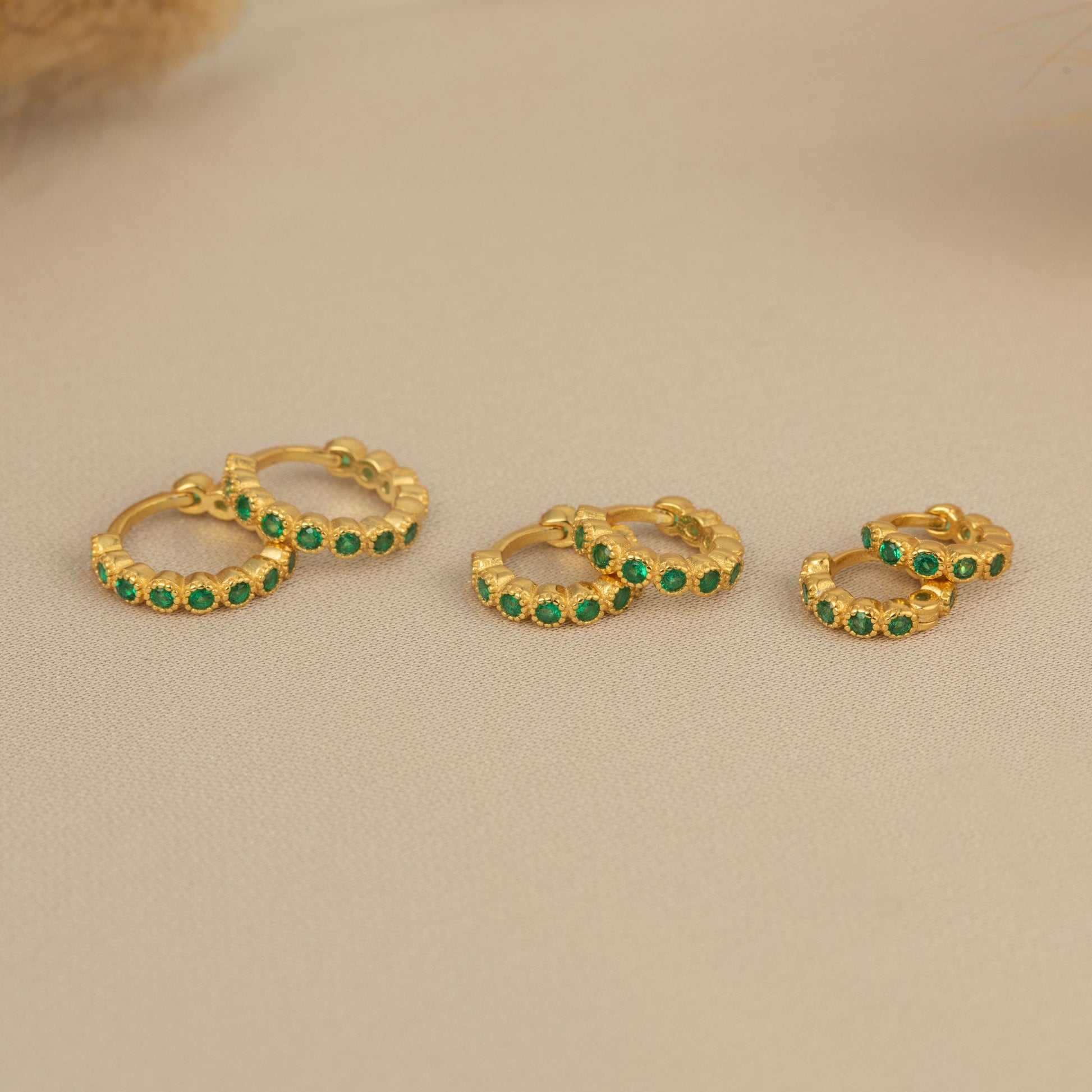 three pairs of green stoned gold hoop earrings