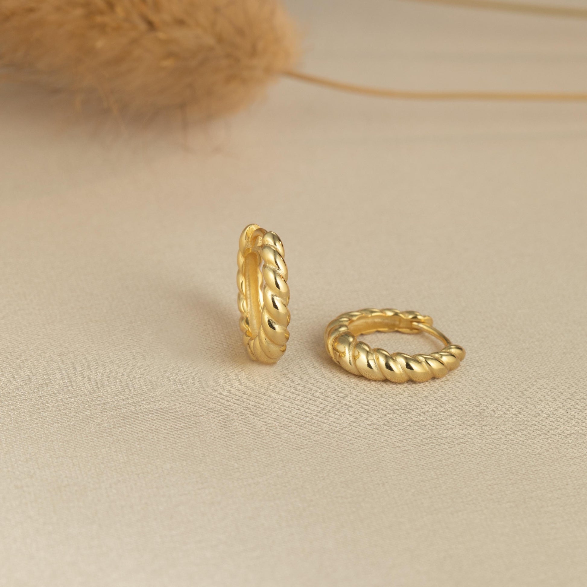 a pair of gold rings sitting on top of a bed