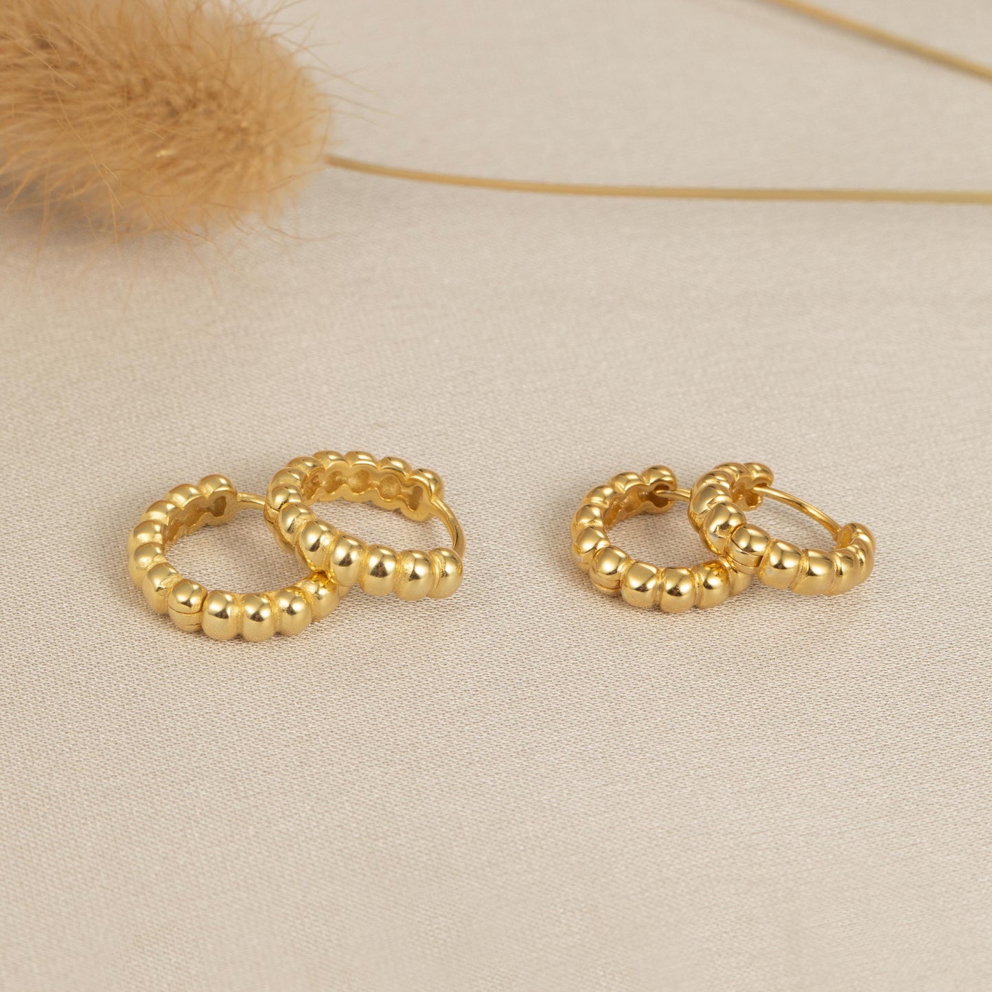 a pair of gold earrings sitting on top of a table