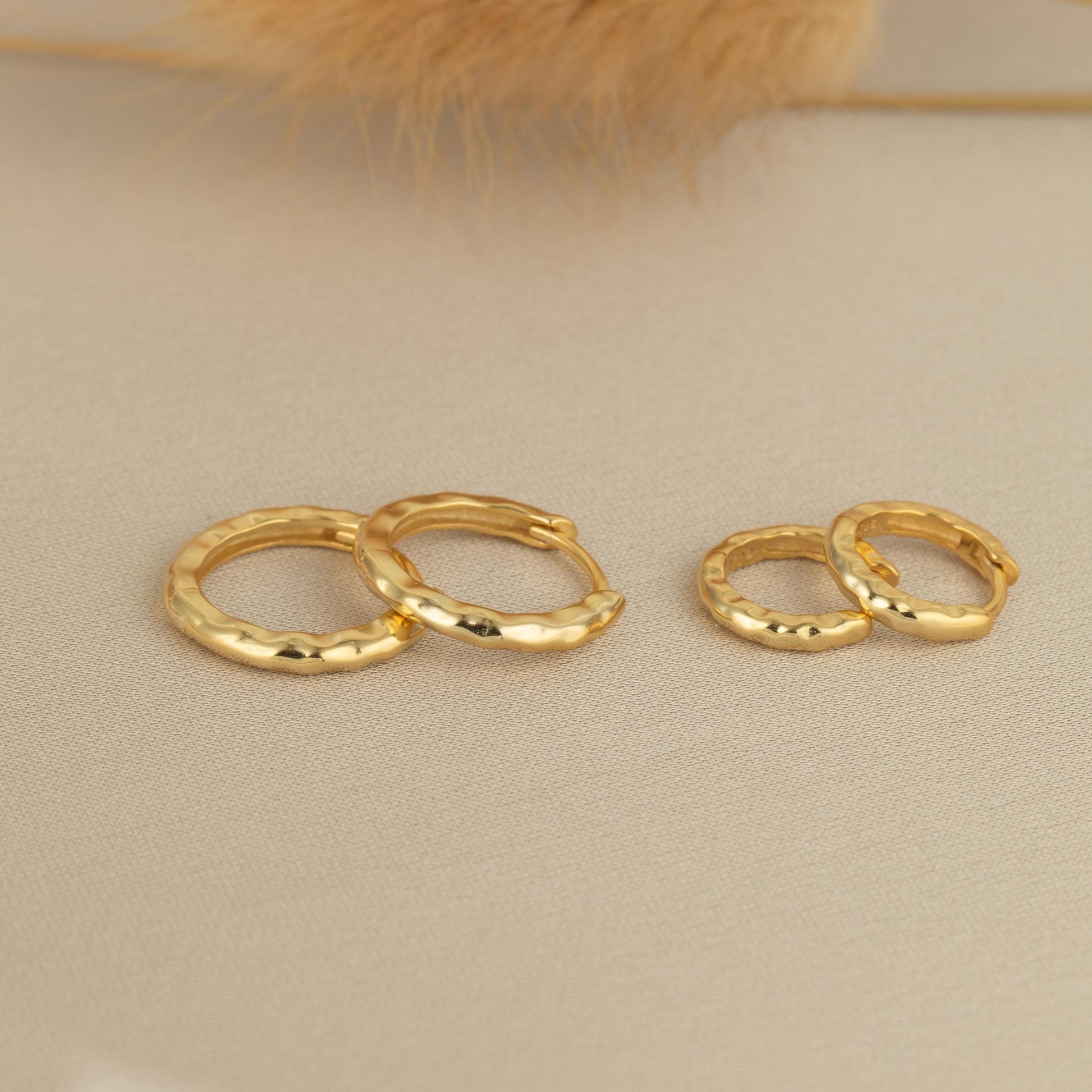 a pair of gold earrings sitting on top of a table