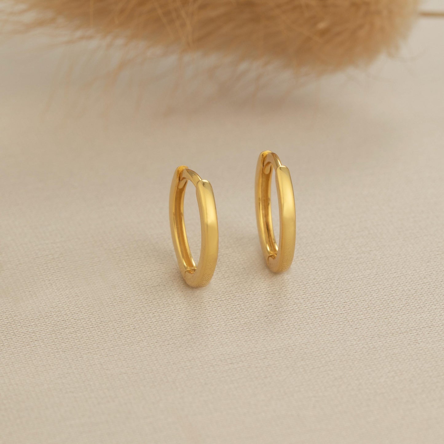 a pair of gold hoop earrings sitting on top of a table