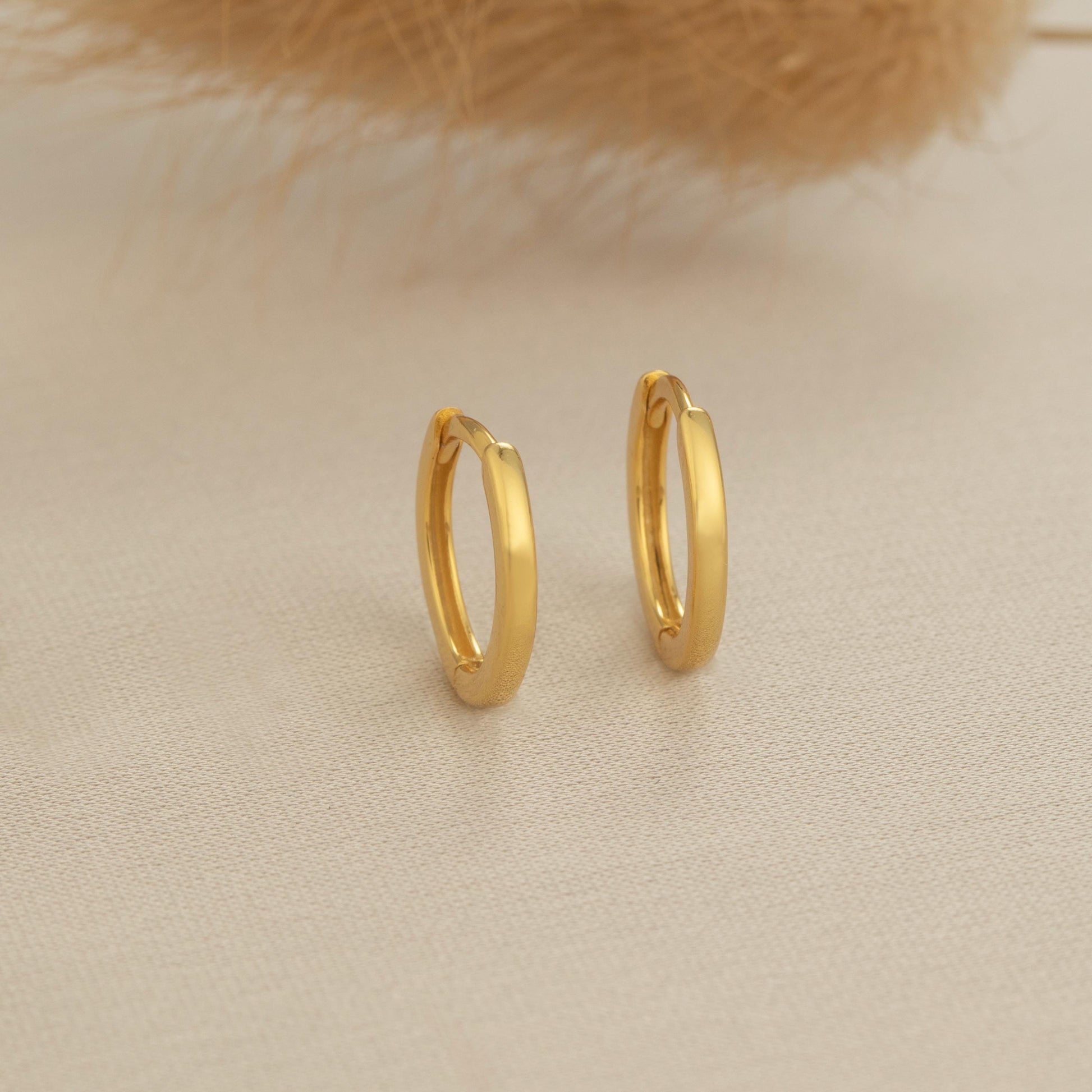 a pair of gold hoop earrings sitting on top of a table
