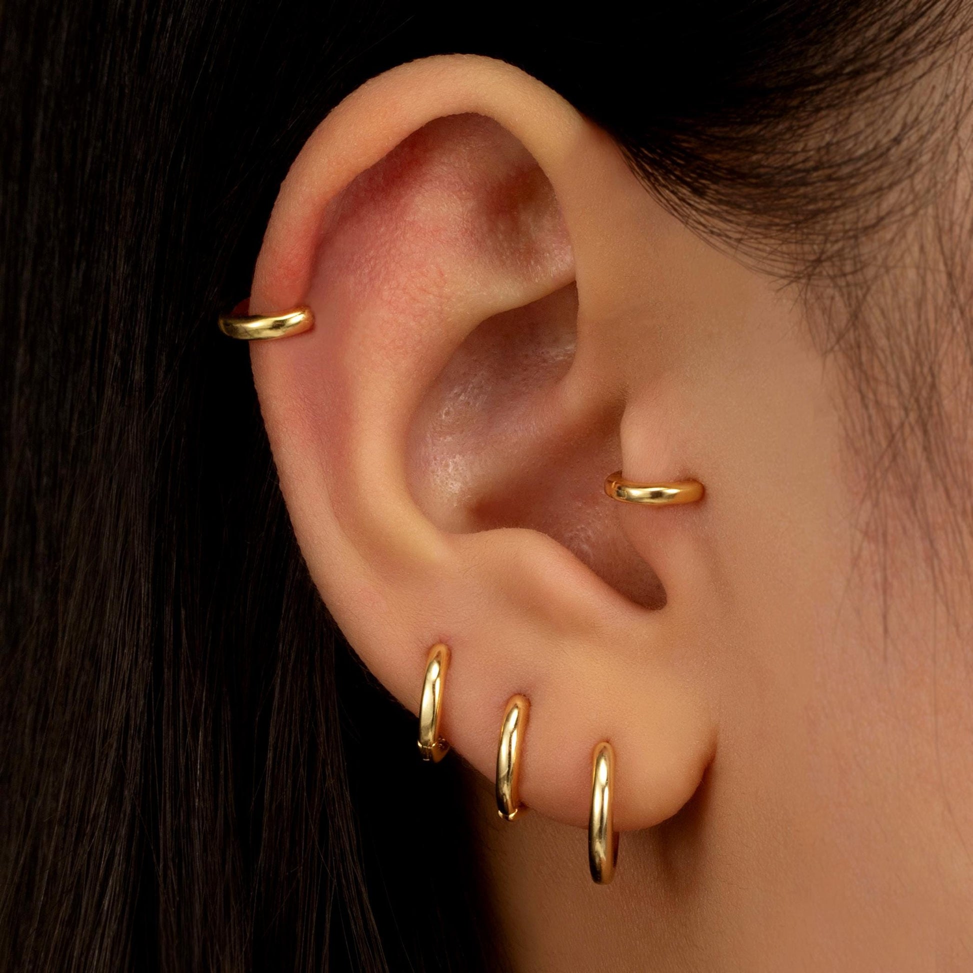 a close up of a person&#39;s ear with two gold rings