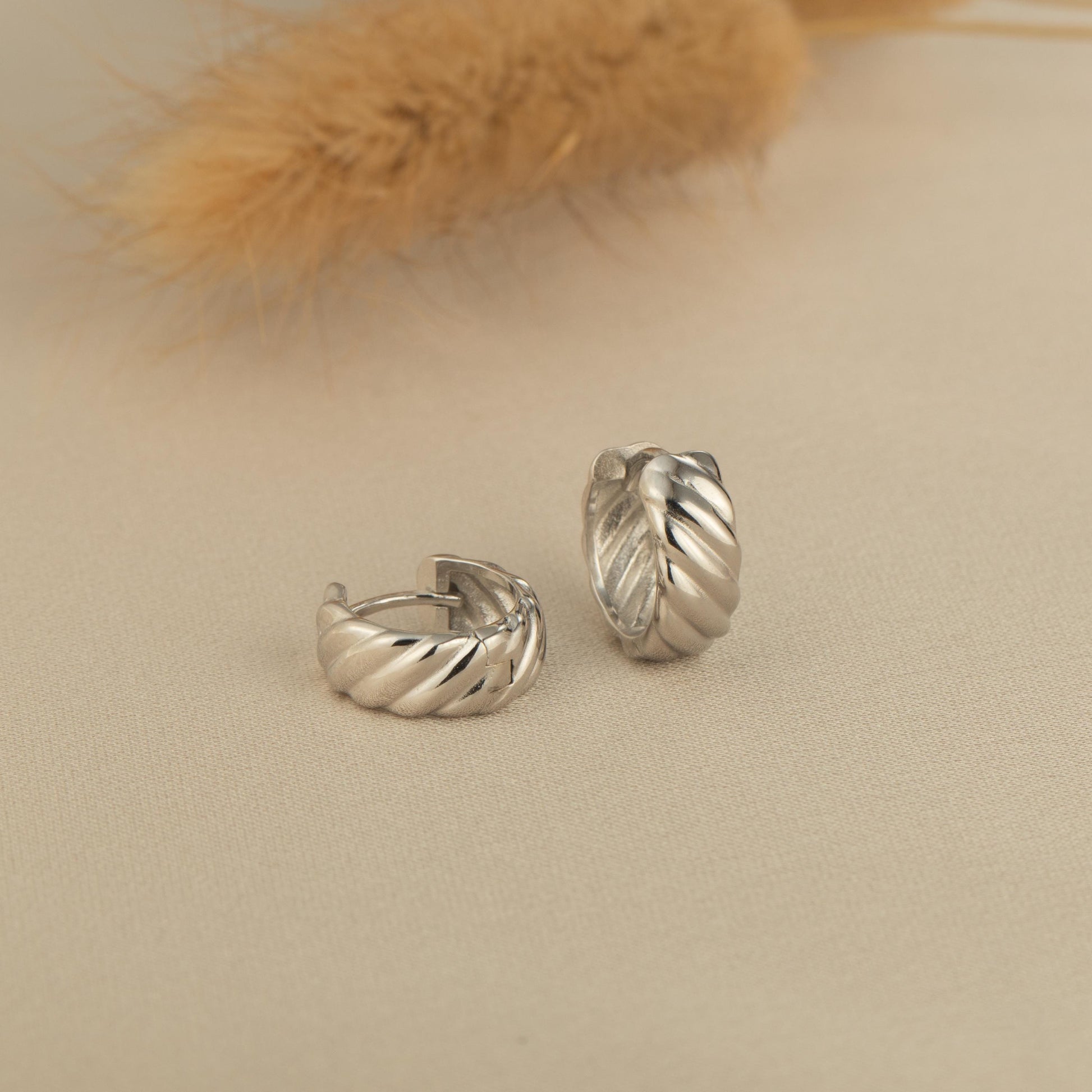 a pair of silver earrings sitting on top of a table