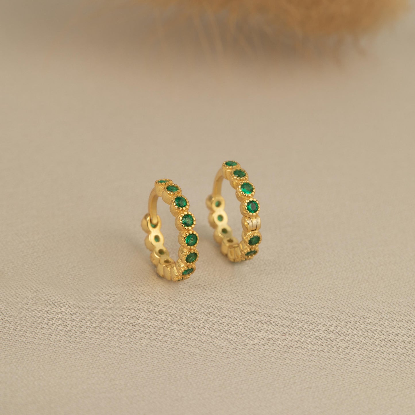 a pair of gold earrings with green stones