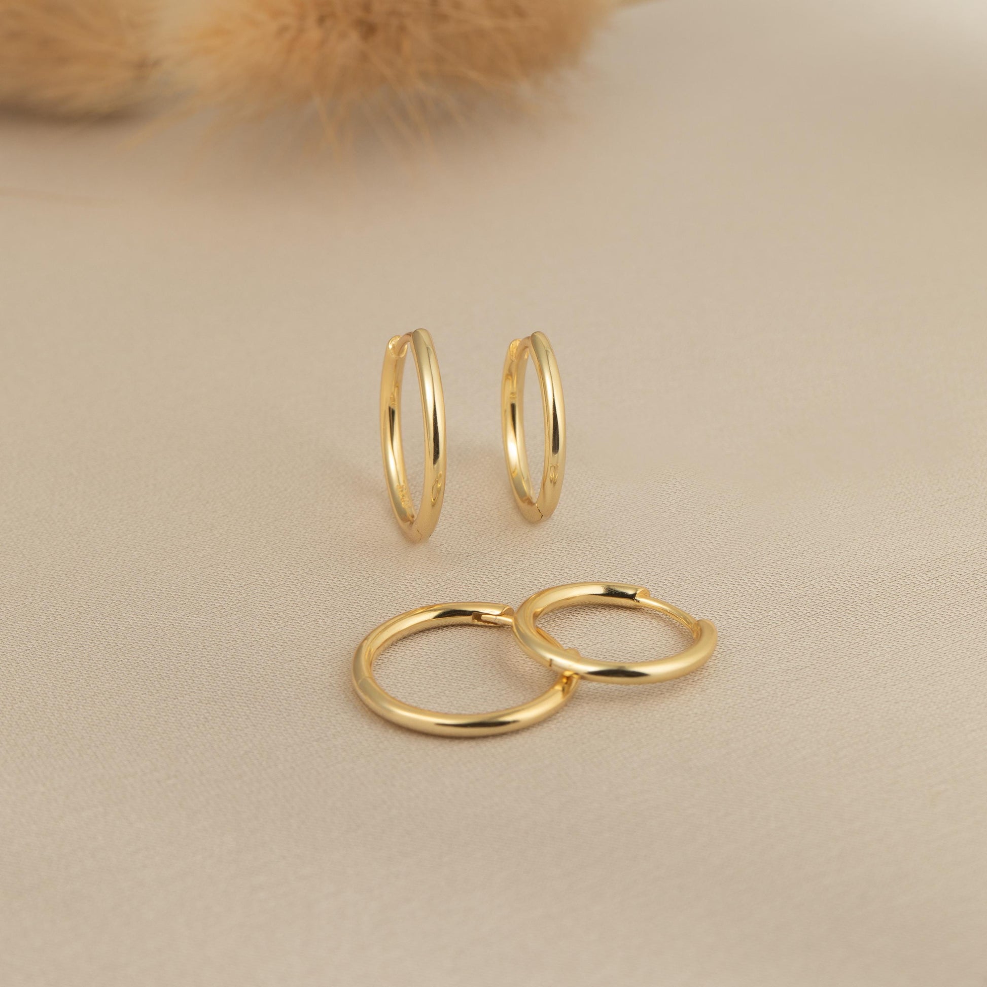 a pair of gold hoop earrings next to a teddy bear