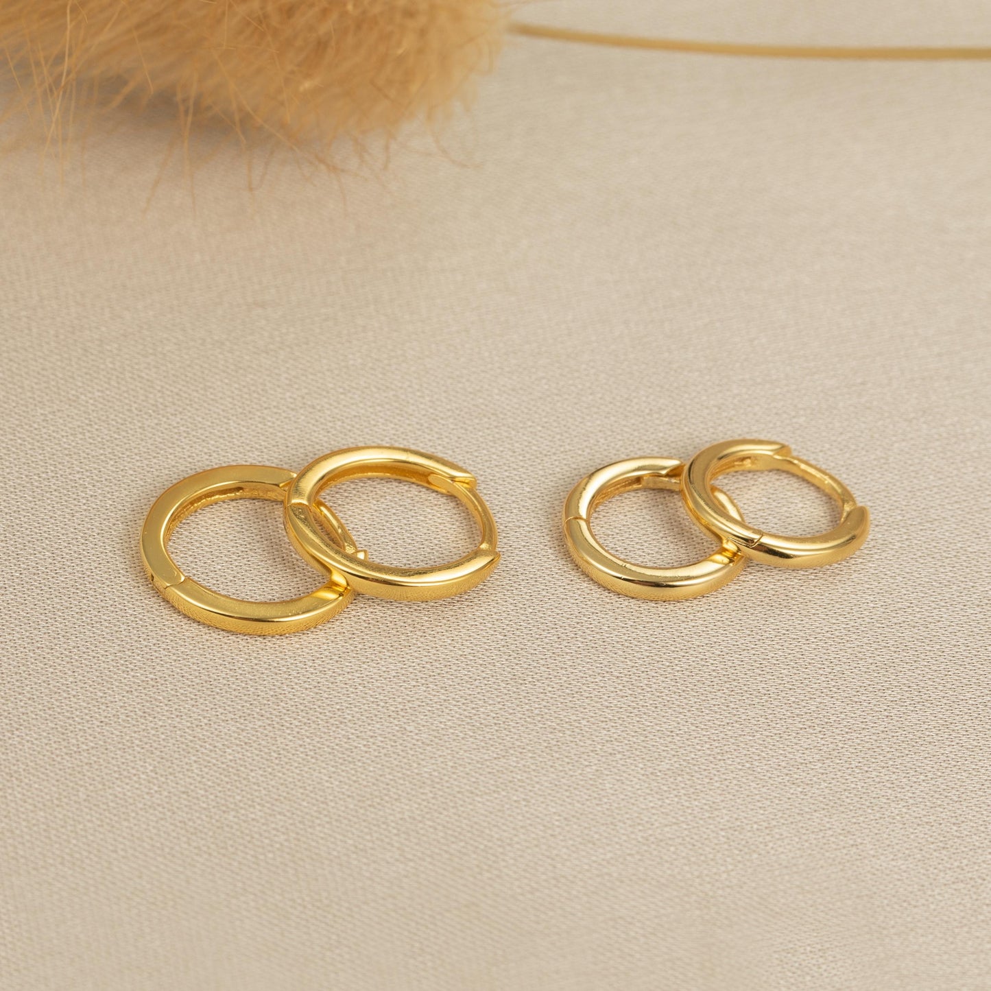 a pair of gold earrings sitting on top of a table