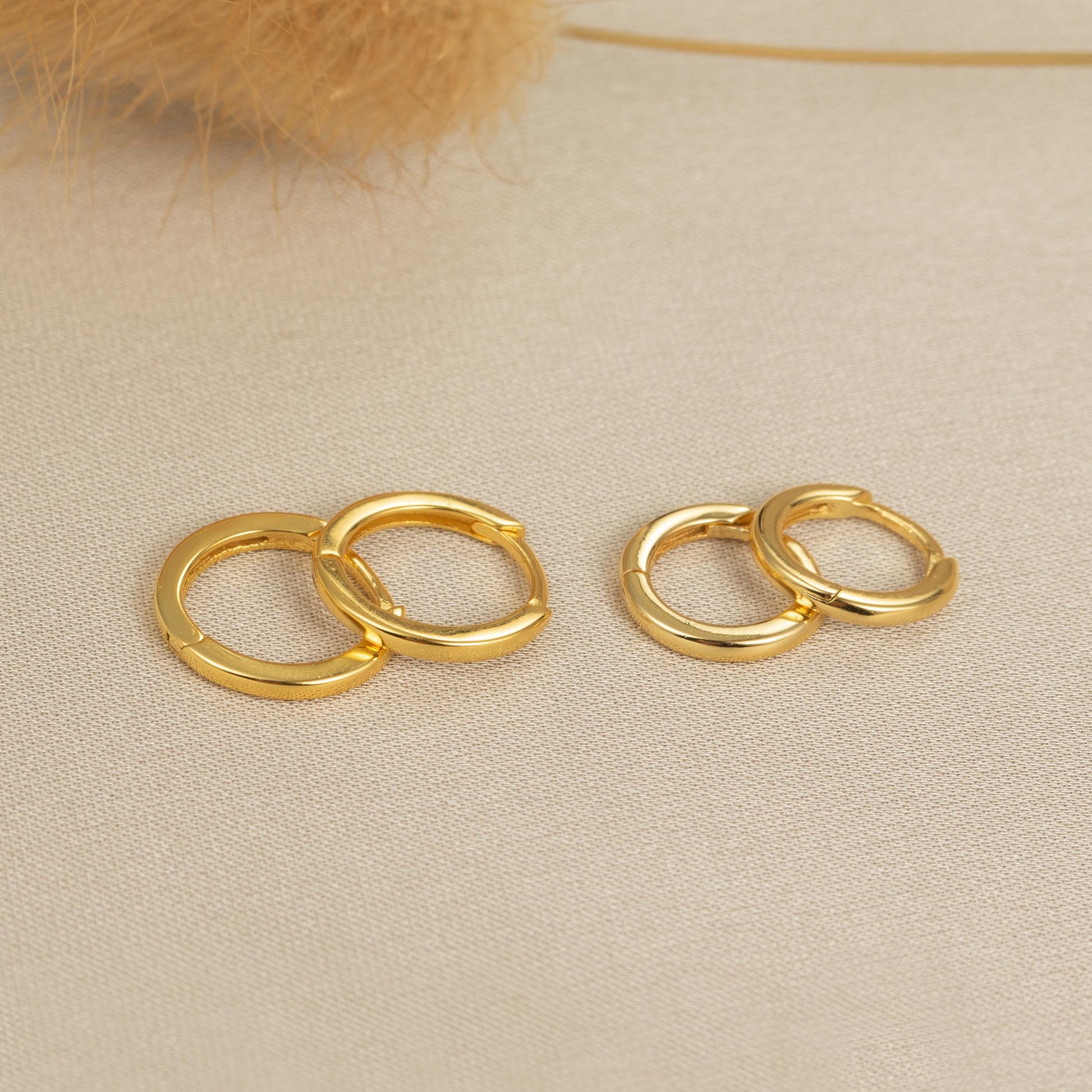 a pair of gold earrings sitting on top of a table