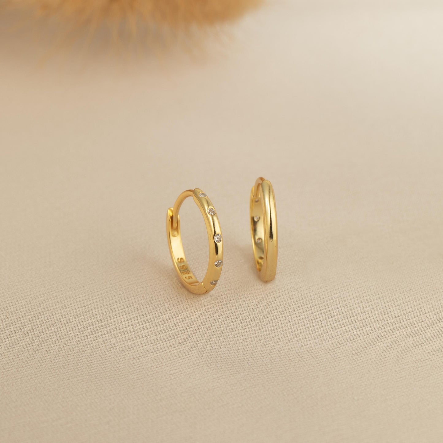 a pair of gold hoop earrings sitting on top of a table